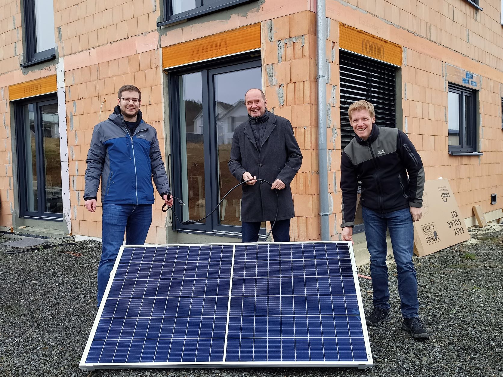 Gewinner Lukas Jung (links) vor seinem neuen Eigenheim mit dem Solarmodul. Umweltdezernent Heinz Schreiber (Mitte) und Klimaschutzmanager Ingo Dorsten (rechts) gratulieren. Foto: Lahn-Dill-Kreis