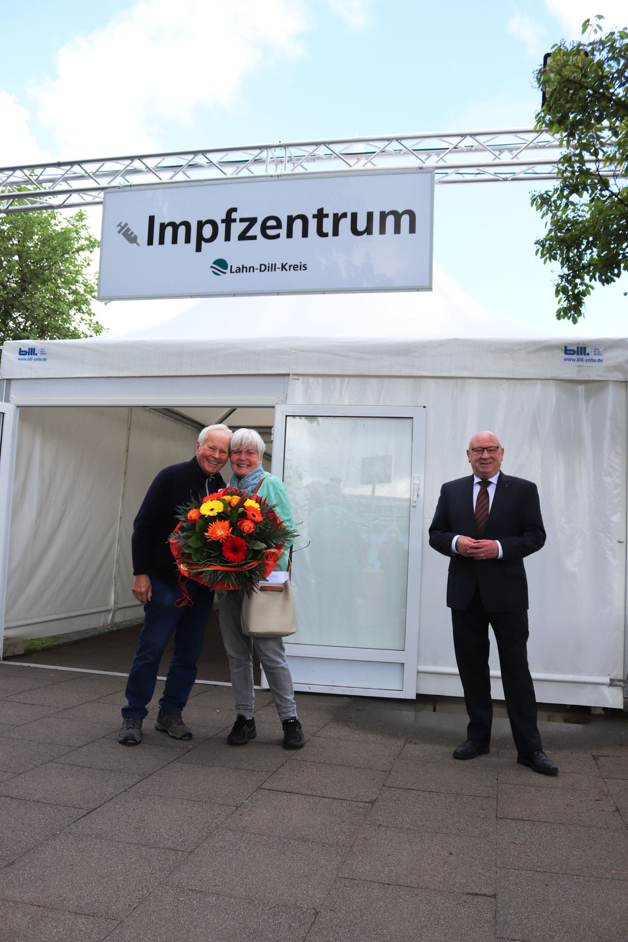 Impfung und Blumen: Landrat Wolfgang Schuster überreichte Christa Bellinghausen aus Driedorf-Mademühlen ein Präsent zur 100.000. Impfung im Landkreis. Mit dabei ist Ehemann Willi Bellinghausen. (Foto: Lahn-Dill-Kreis)