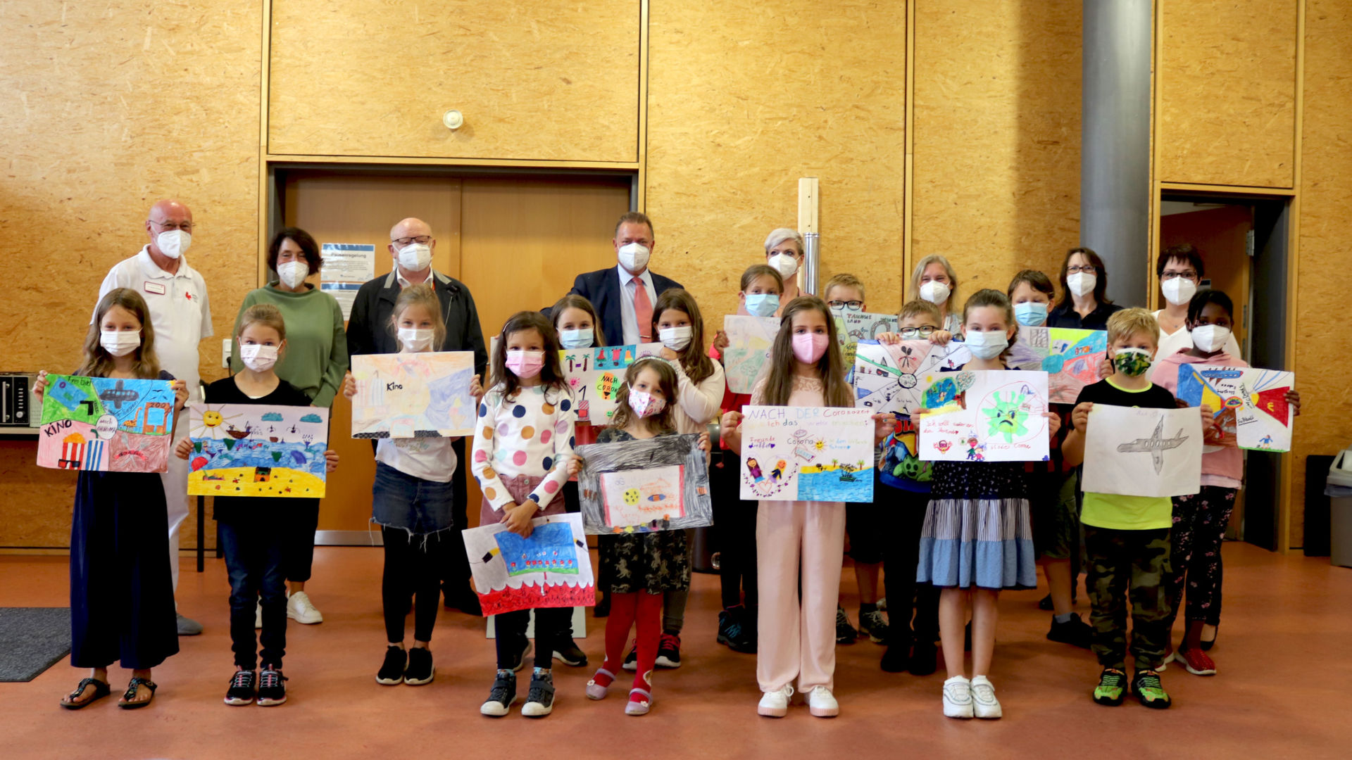 Die Schülerinnen und Schüler der Grundschule Leun und Barbara Hoyer (hinten, Fünfte von links) sind stolz auf ihre Werke. Dr. Walter Staaden, medizinischer Leiter des Impfzentrums (hinten, Erster von links), Landrat Wolfgang Schuster (hinten, Dritter von links) und Reinhard Strack-Schmalor, Leitung des Impfzentrums (hinten, Vierter von links), bedanken sich bei allen Beteiligten für den Einsatz und die Kreativität. (Foto: Lahn-Dill-Kreis)