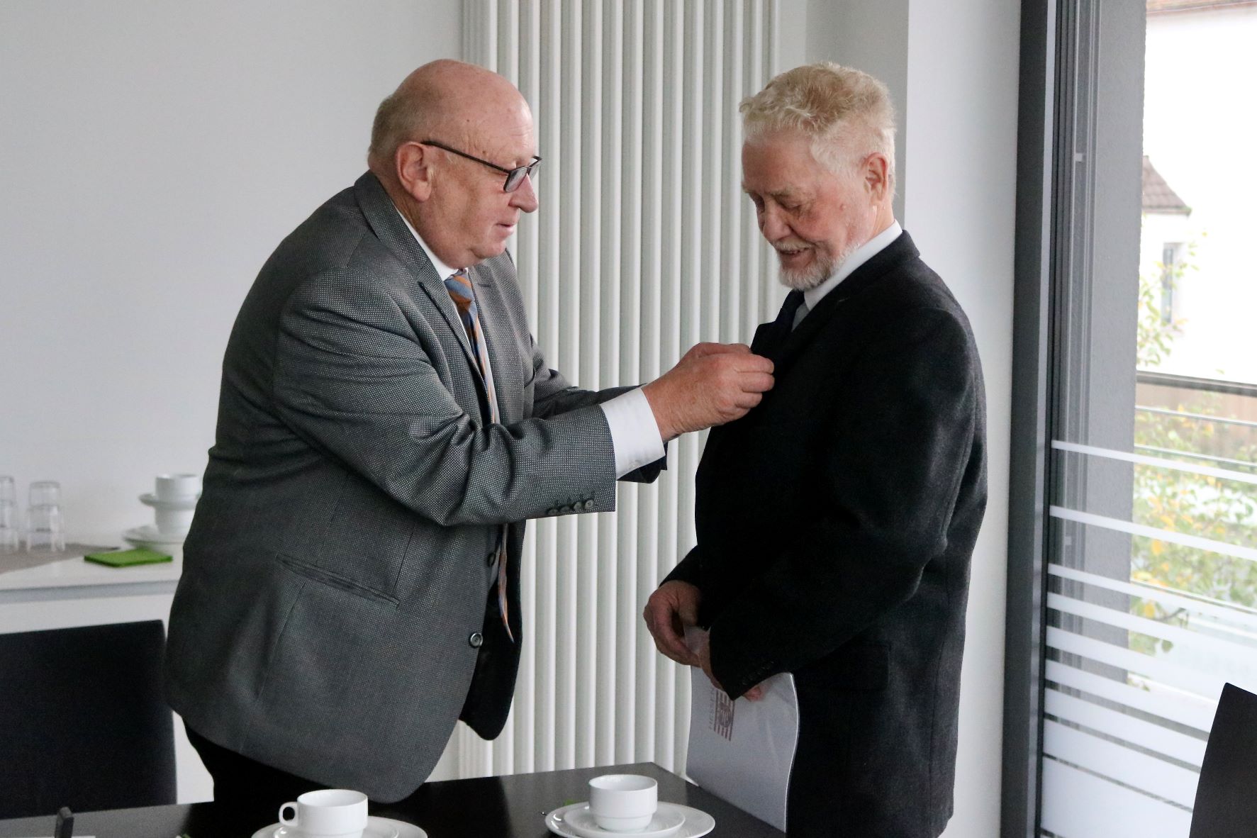 Landrat Wolfgang Schuster (links) brachte nach Überreichen der Urkunde auch die hessische Ehrennadel an Paul Hartmanns Jackett an. Foto: Lahn-Dill-Kreis