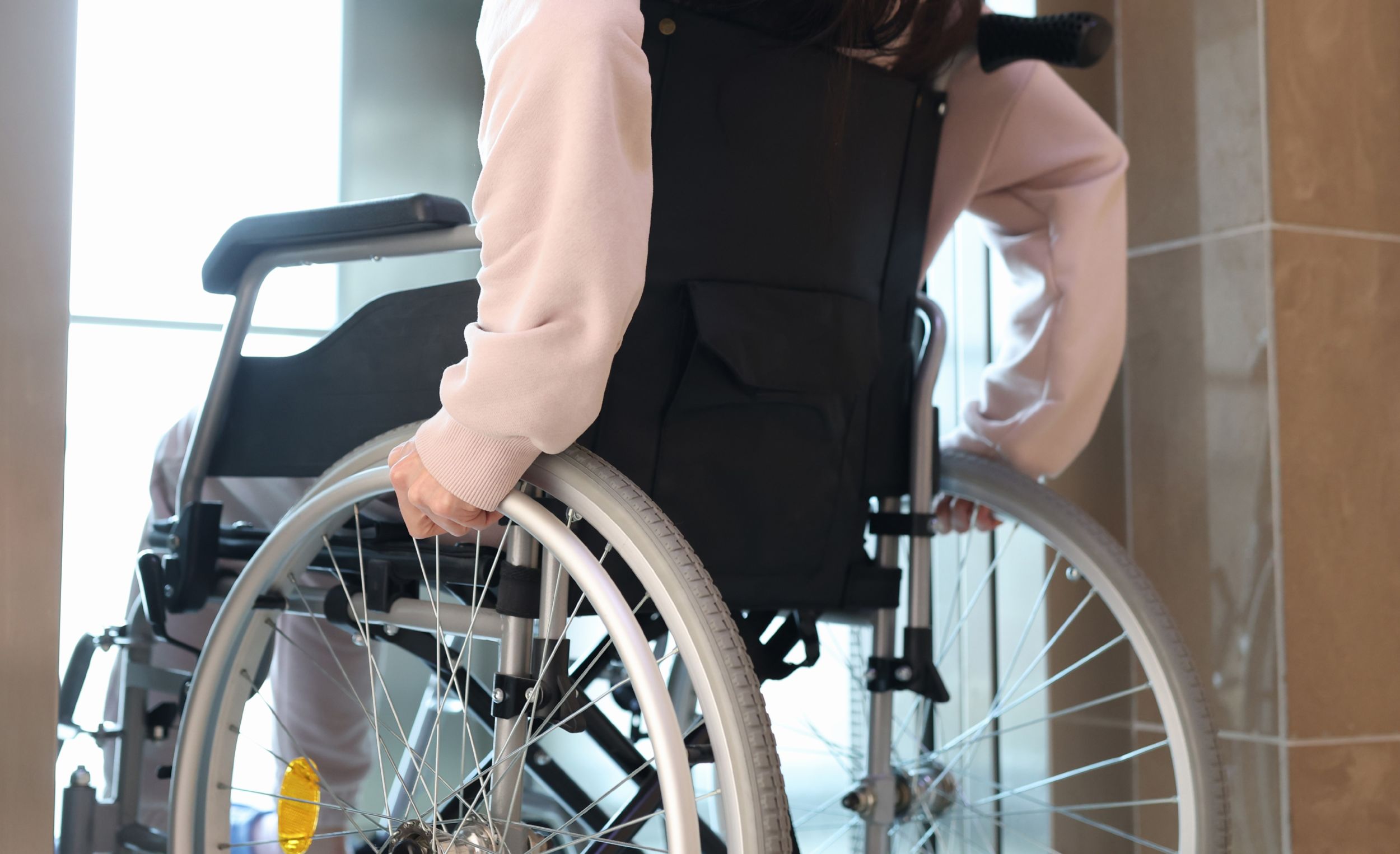 Eine Frau fährt mit einem Rollstuhl in einen Fahrstuhl.