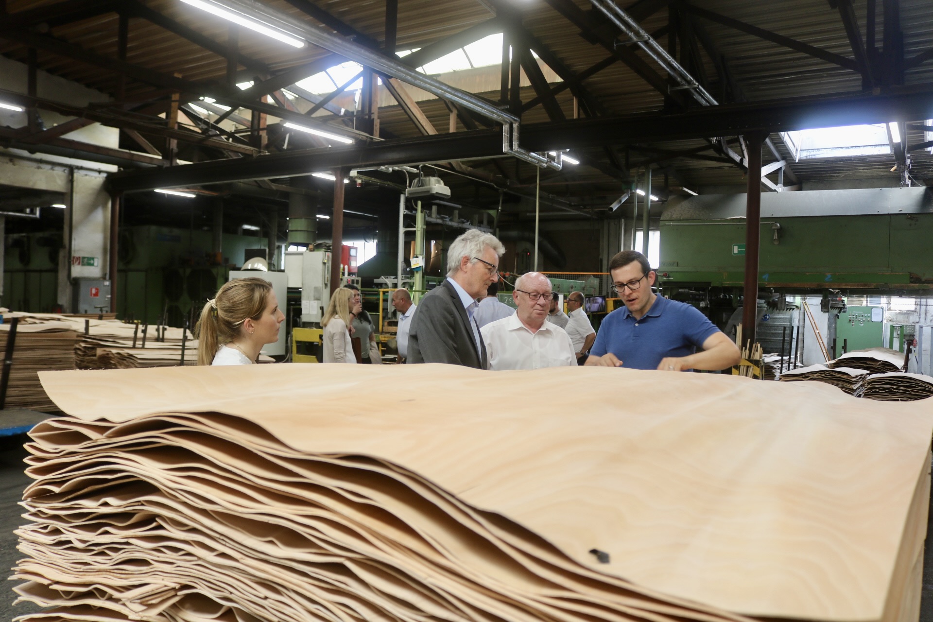 Die Teilnehmenden des Unternehmensbesuch betrachten das Furnierholz und bekommen dazu etwas erklärt.