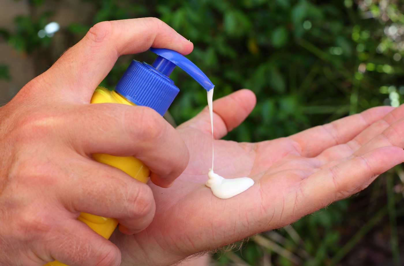 Sonnencreme Sonnencreme wird auf eine Hand aus einem Pumpspender gegeben.