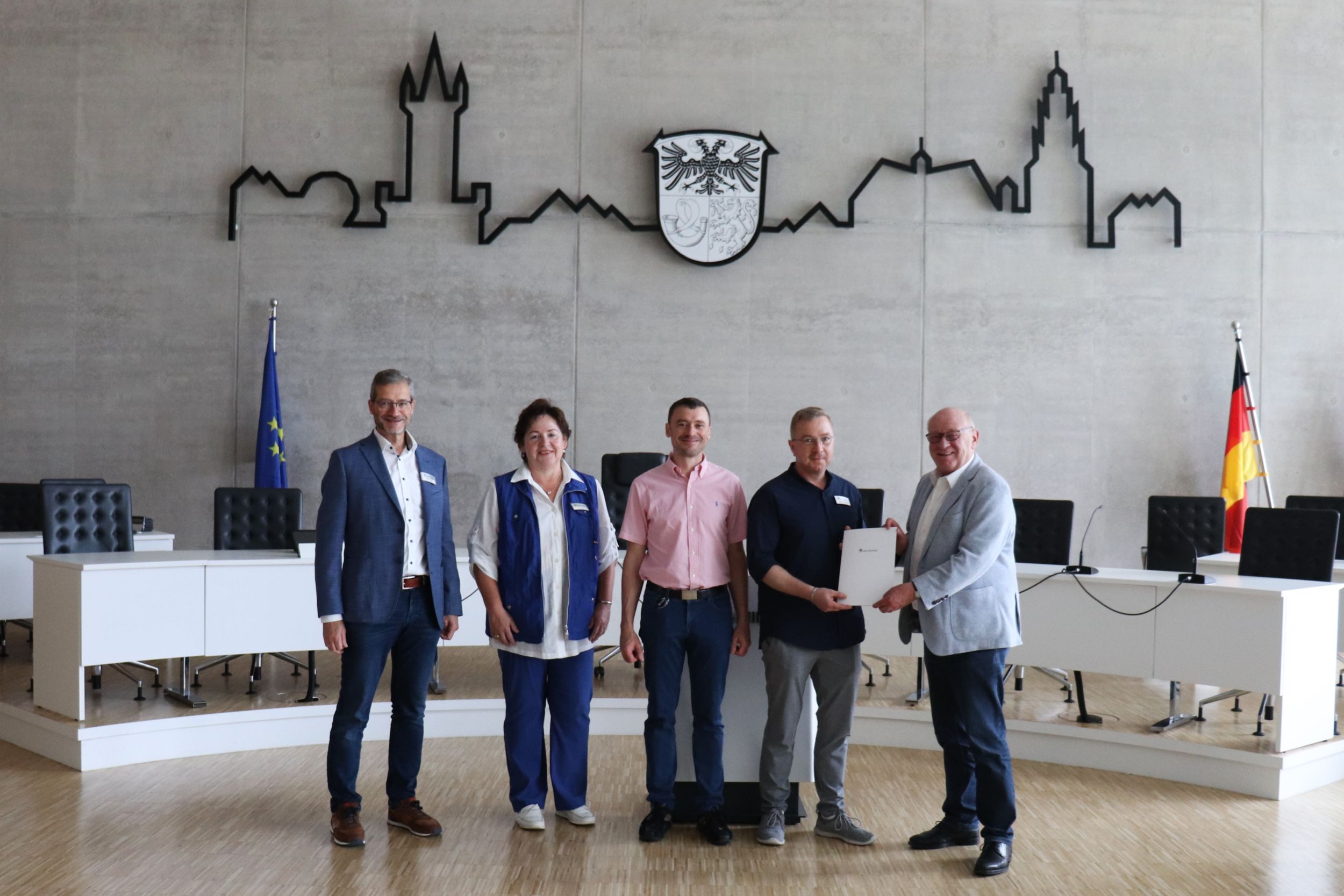 Der Jubilar Ralf Burmeister wird von Landrat Wolfgang Schuster, Jörg Kring und Andrea Volk beglückwünscht, alle lächeln in die Kamera.