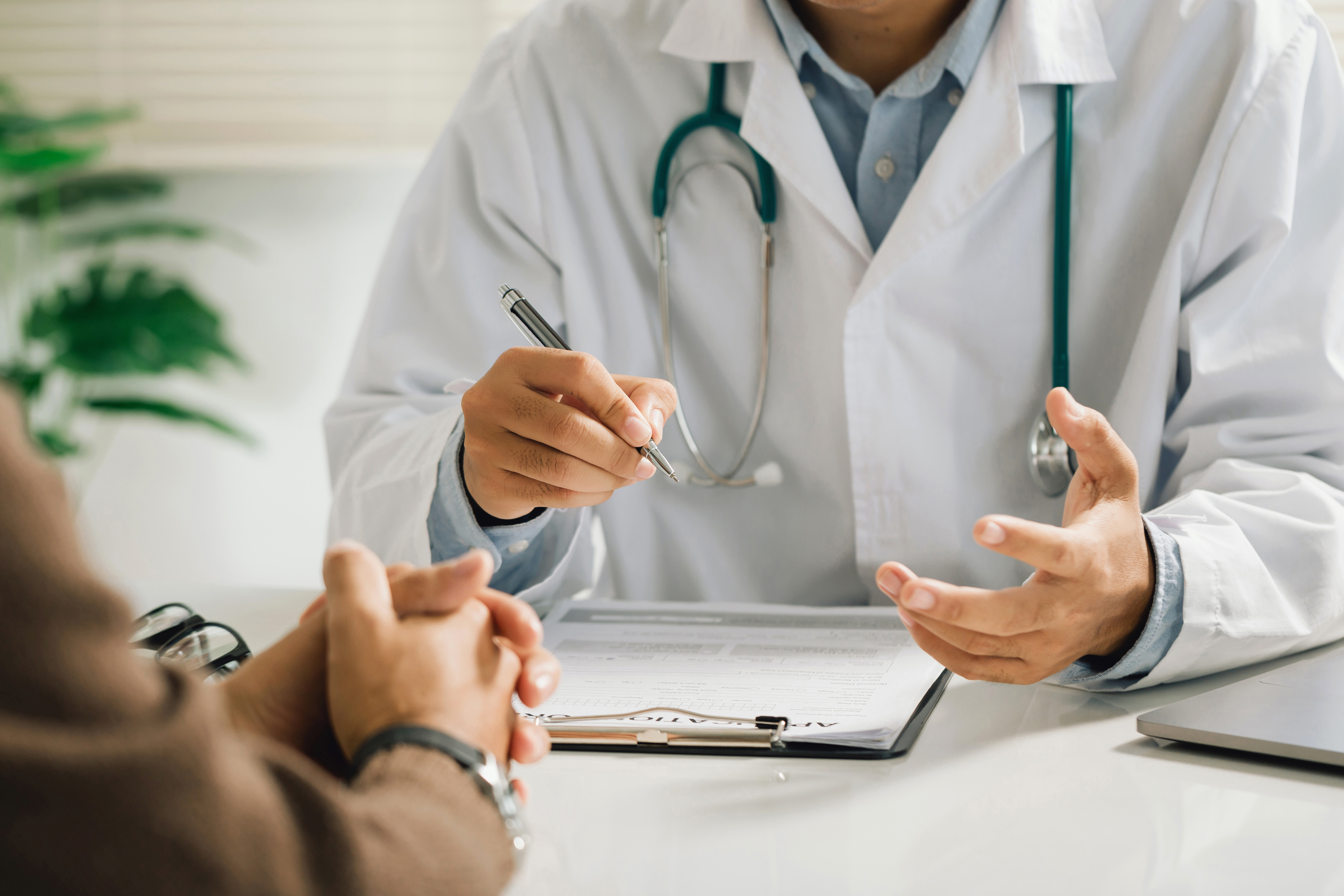 Symbolbild: Ein Arzt spricht mit einem Patienten und macht Notizen. Foto: Adobe Stock