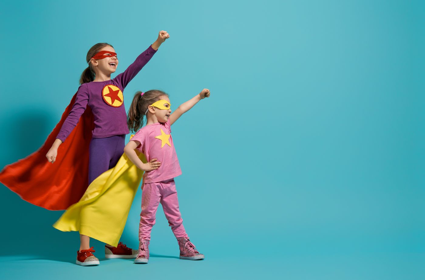 Zwei Kinder posieren als Superhelden vor einem neutralen Studiohintergrund. Foto: children playing superhero von Choreograph von Getty Images via Canva.com