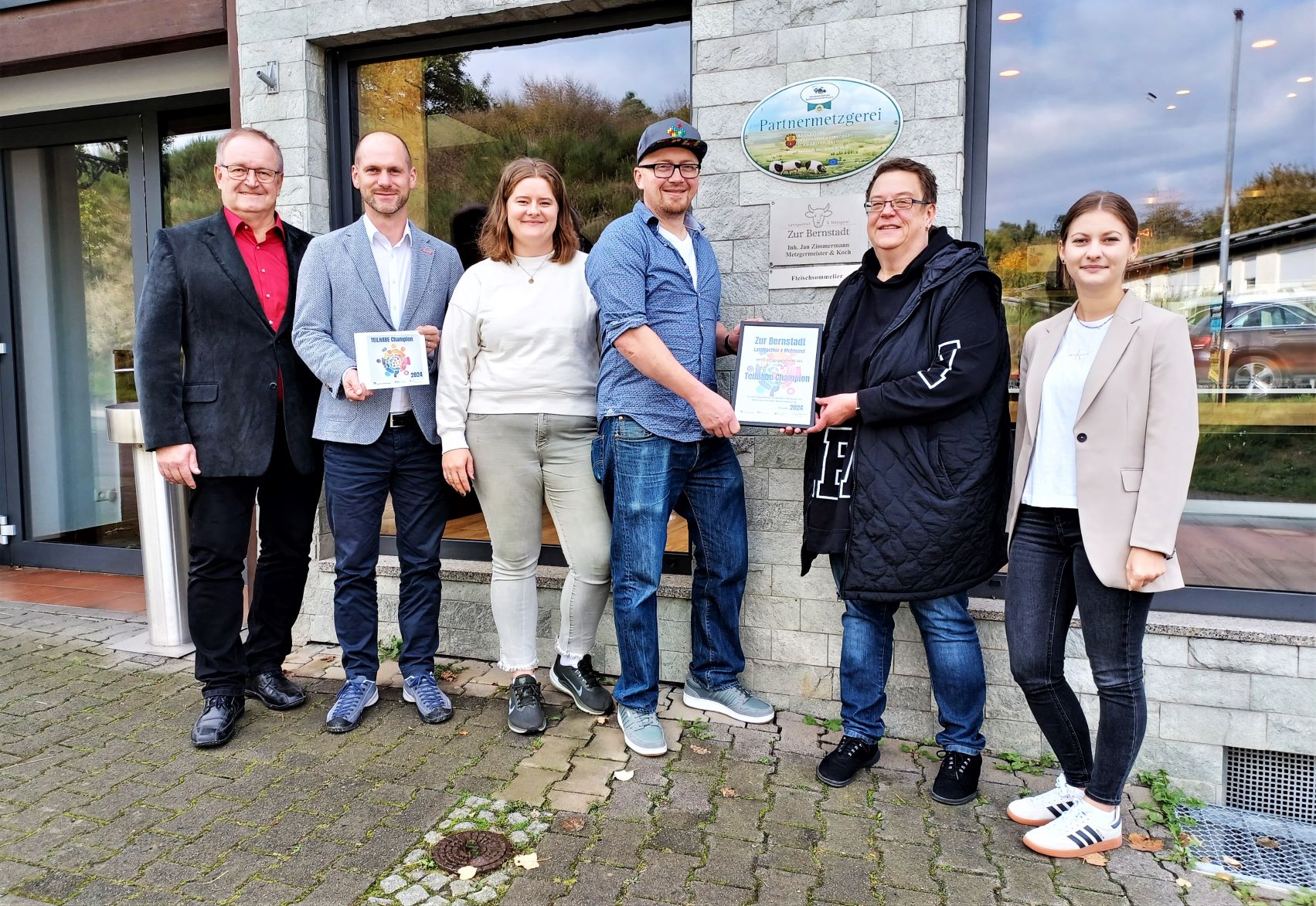 236_Teilhabechampion Zur Bernstadt Zum zweiten Mal ging die Auszeichnung „Teilhabechampion des Monats“ an ein Unternehmen in Schöffengrund. (v. links): Michael Peller, Niklas Kraft-Schwiebs, Vivien Zimmermann, Jan Zimmermann, Susanne Eiben kommunale Behindertenbeauftragte des Lahn-Dill-Kreises, Kim Stahl, Wirtschaftsförderung des Lahn-Dill-Kreises. Foto: Monika Mundt