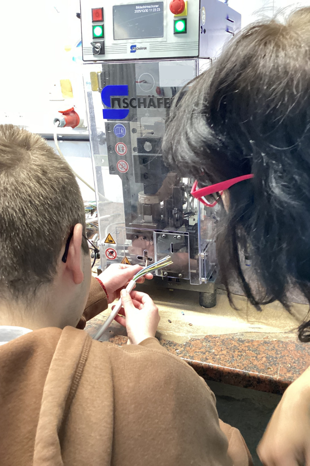 DUODay 2025_1 Julian mit DUO-Partnerin an Crimpmaschine. Foto: Kommunales Jobcenter Lahn-Dill